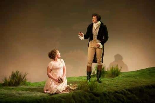 A young woman kneels while a man stands over her, speaking in Sense and Sensibility The Musical.