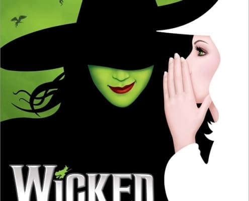 Wicked witch dressed in white whispering to witch dressed in black with a green face