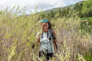 A woman smiles as she walks through tall grass