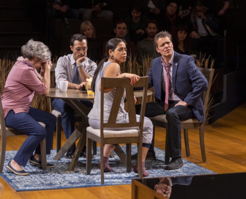A group of people sit at a dinner table onstage in twenty50