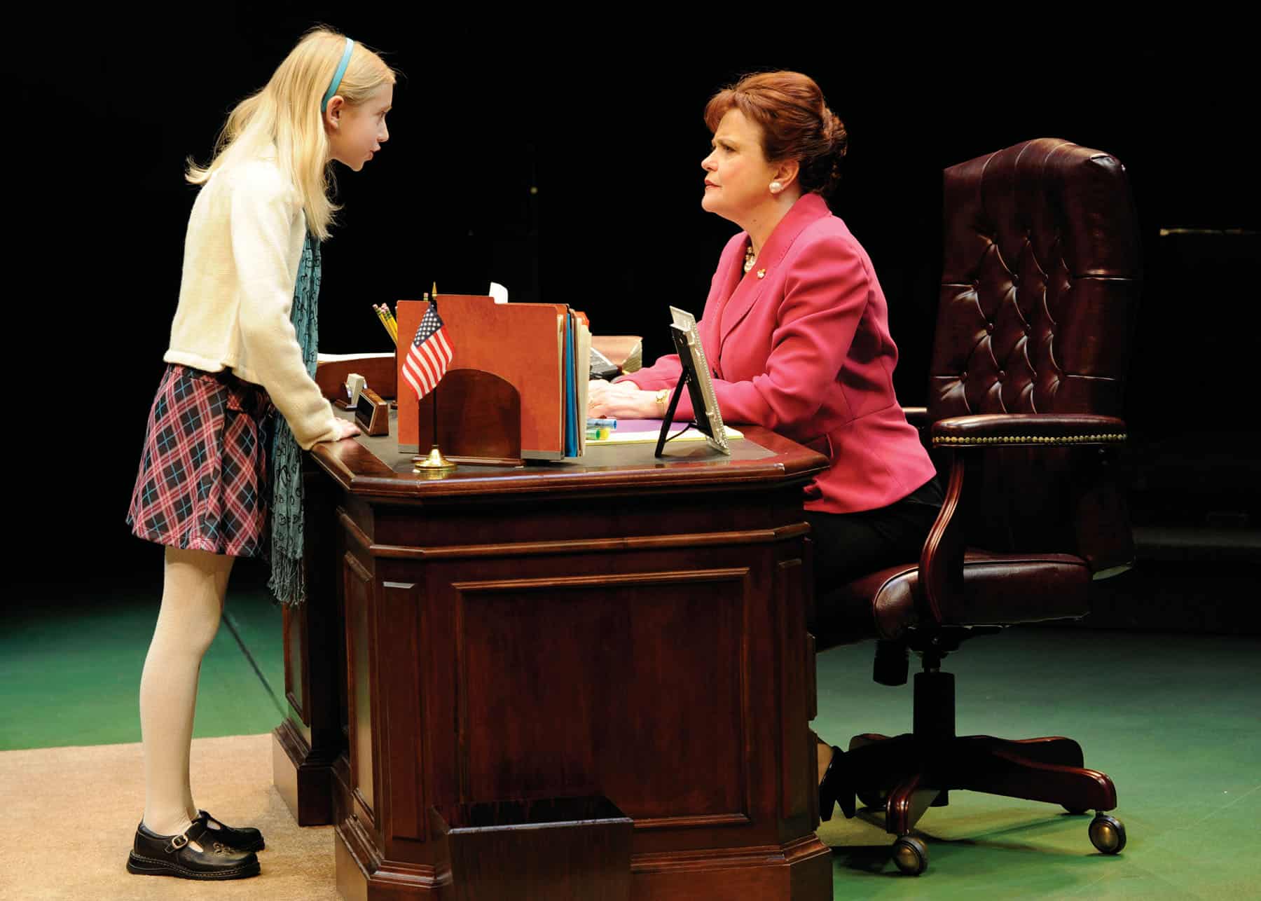 A young girl confronts a professional woman seated at a desk in Dusty and the Big Bad World