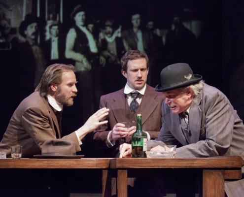 Three men huddle around a bar deep in discussion in Great Wall Story