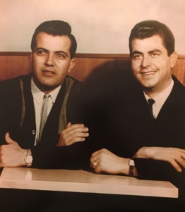 A sepia toned photograph of two men seated in a booth