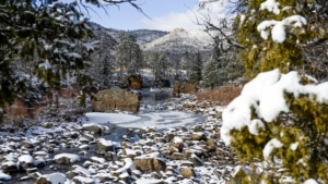 A river surrounded by trees with a light amount of snow