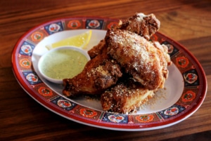 A plate of fried chicken with dipping sauce dusted with white powder