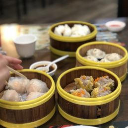 Four steamer baskets with dumplings inside