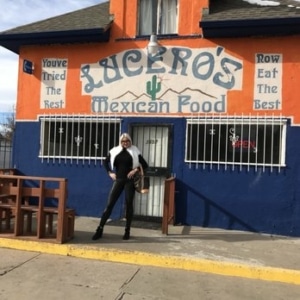 A woman poses in front of Lucero's colorful building