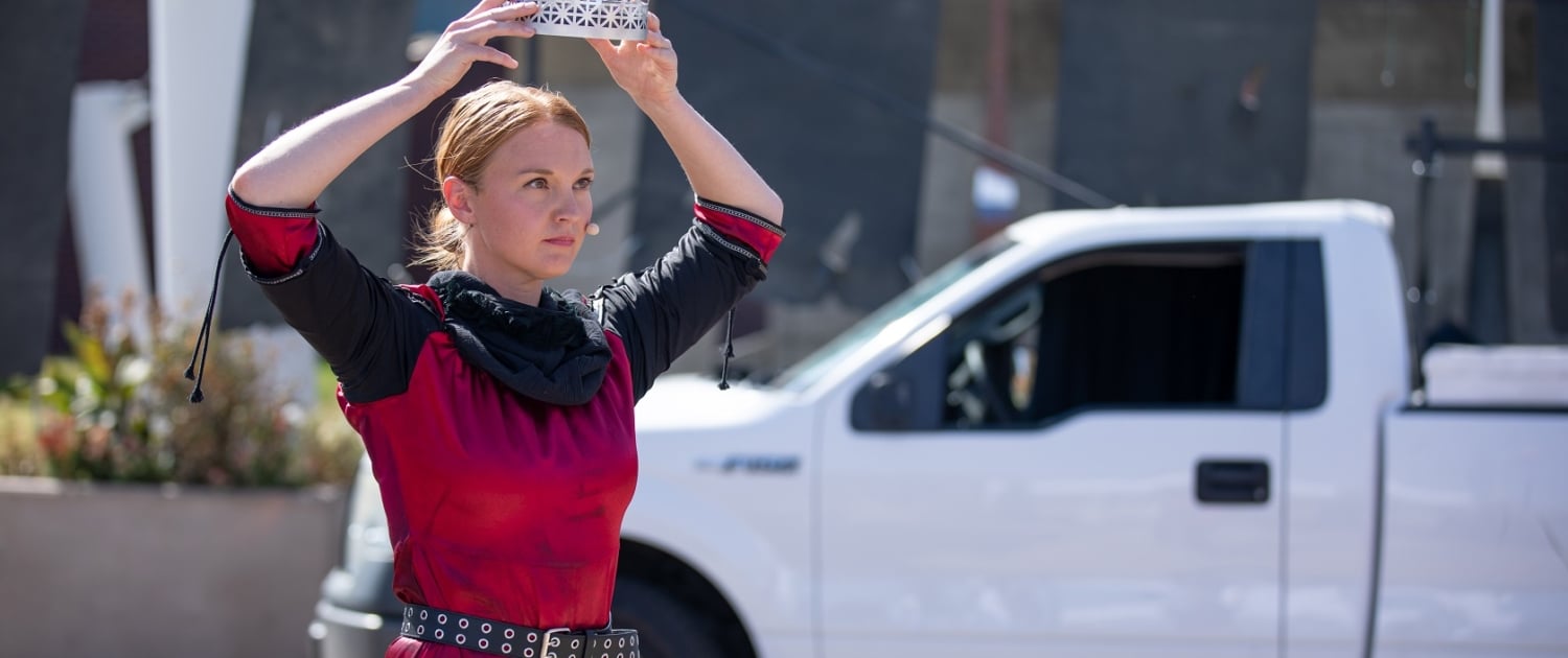 An actor places a crown on her head during a performance of Macbeth