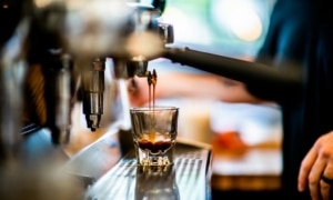 An espresso machine fills a small glass