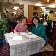 Two women are seated at a table and smile