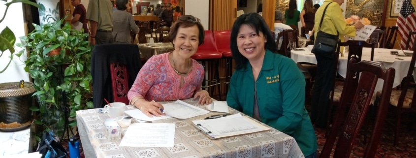 Two women are seated at a table and smile