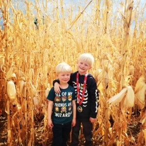 Two children stand outside a corn maze