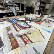 A hand-painted vest is laid out on a workstation