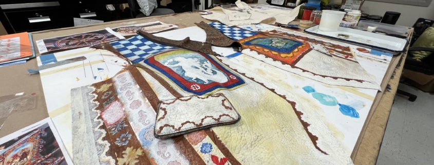 A hand-painted vest is laid out on a workstation