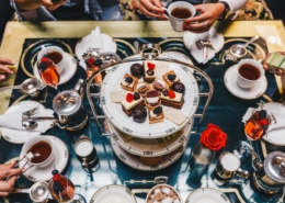 A dessert tower in the center of a table crowded with plates and treats