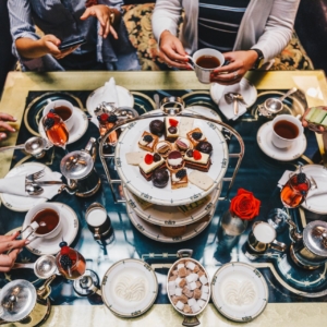 A dessert tower in the center of a table crowded with plates and treats