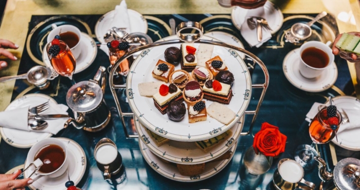 A dessert tower in the center of a table crowded with plates and treats