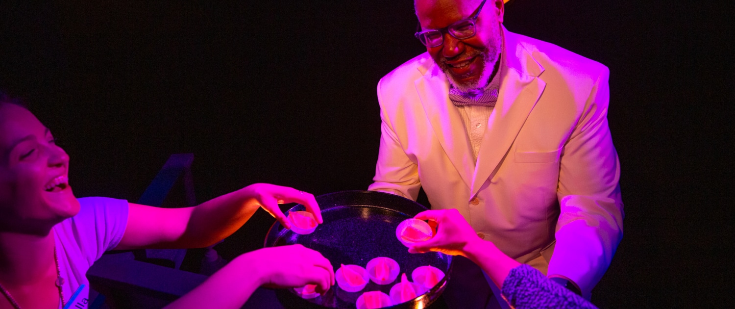 A person holds out a tray of snacks to several hands