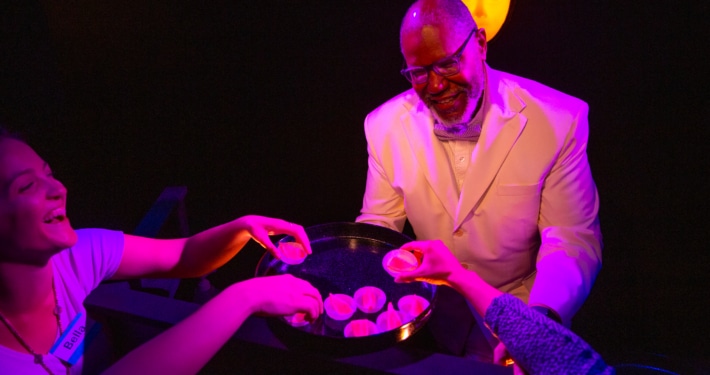 A person holds out a tray of snacks to several hands