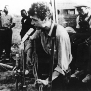 A black and white photograph of Bob Dylan playing guitar