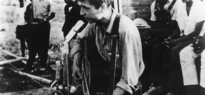 A black and white photograph of Bob Dylan playing guitar