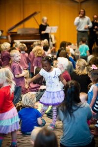 A large group of children are dancing at an Inside the Orchestra event