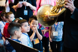 Children watch as a musician plays a horn