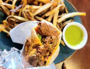 A close up of a gyro with fries