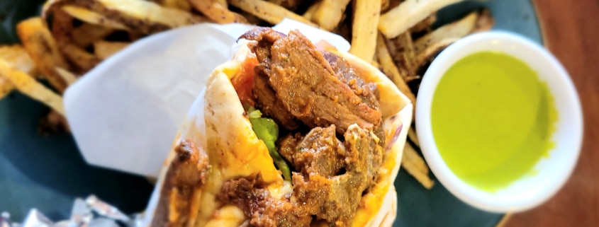 A close up of a gyro with fries