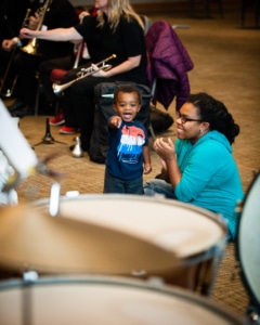 A child laughs and points at a drum set