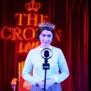 A woman stands in front of an old fashioned microphone