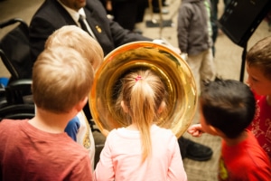 A child stands with her head inside the wide end of a tuba