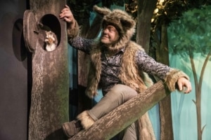 The wolf looks at a squirrel peeking out from a tree
