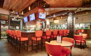 A sports bar with televisions and orange stools at the bar