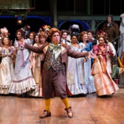 group of actors in period costumes performing on stage.