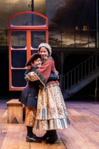 Two children embrace onstage in A Christmas Carol