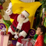 A child smiles with Santa surrounded by gifts