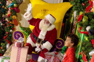 A child smiles with Santa surrounded by gifts