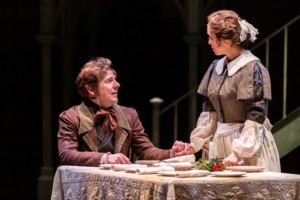 A mn seated at a table speaks with a woman in A Christmas Carol