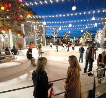 People mill around and skate at an outdoor ice rink