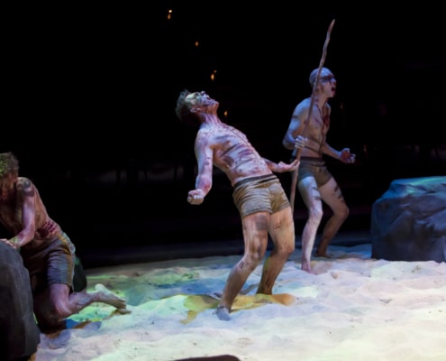 Three actors covered in markings yell onstage in Lord of the Flies