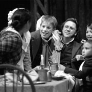 The Cratchit family crowds around a table in A Christmas Carol