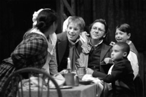 The Cratchit family crowds around a table in A Christmas Carol