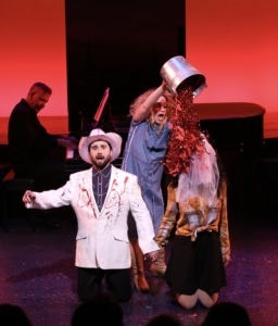 Two people kneel while soup is dumped on their heads