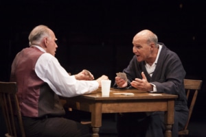 Two older men play cards at a dining table in Death of a Salesman