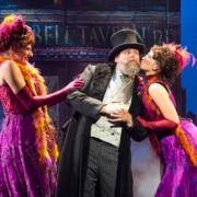 Two women lean in to kiss a man's cheeks in My Fair Lady