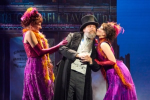 Two women lean in to kiss a man's cheeks in My Fair Lady