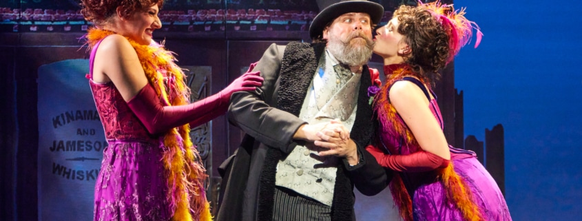 Two women lean in to kiss a man's cheeks in My Fair Lady