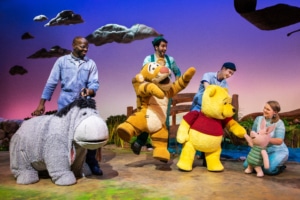 The cast and puppets of Winnie the Pooh pose onstage