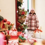 A little girl smiles as she looks into a room filled with gifts at Camp Christmas